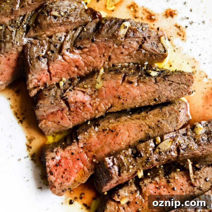 Closeup of bavette steak sliced medium rare on a white plate au jus.