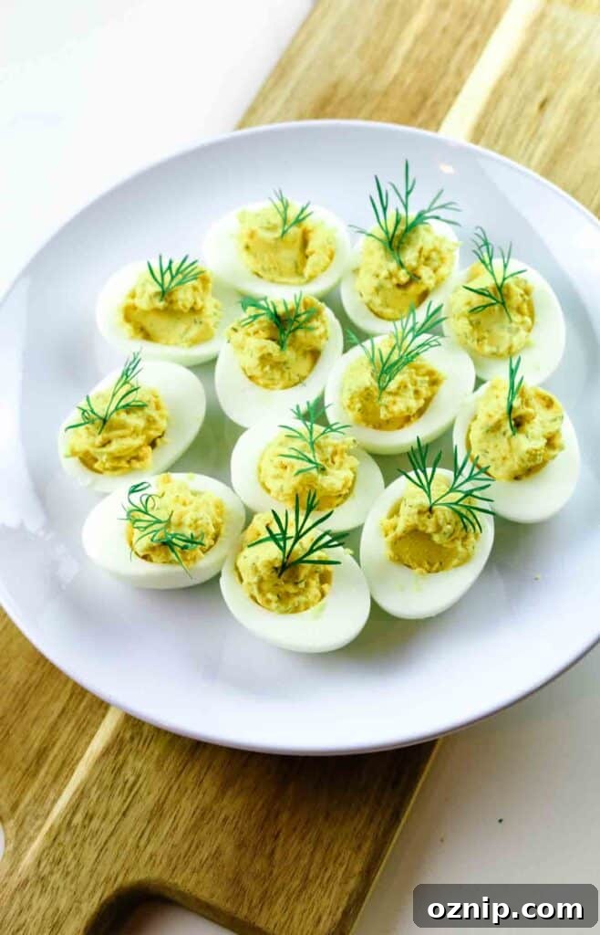 Classic Deviled Eggs Recipe for Parties 5 Deviled eggs on a white platter and a board with dill garnish.