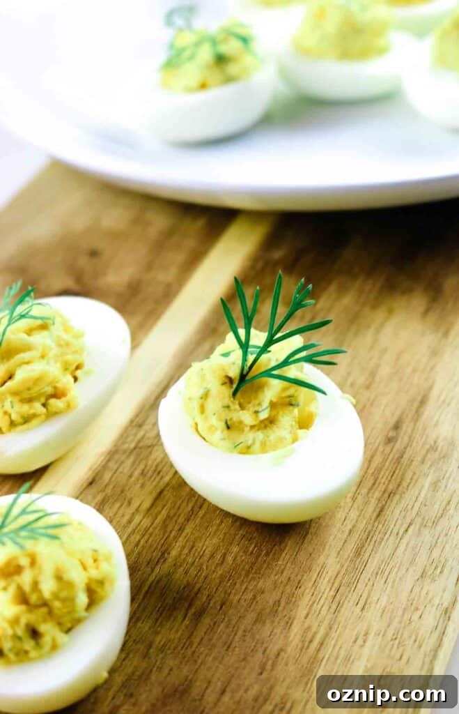 Classic Deviled Eggs Recipe for Parties 8 Deviled egg with a sprig of dill as garnish on a cutting board.
