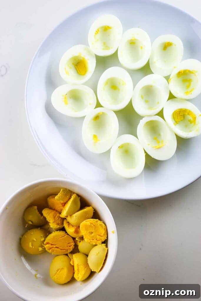 Classic Deviled Eggs Recipe for Parties 9 Cooked egg white separated on a white platter and egg yolks in a ramekin.