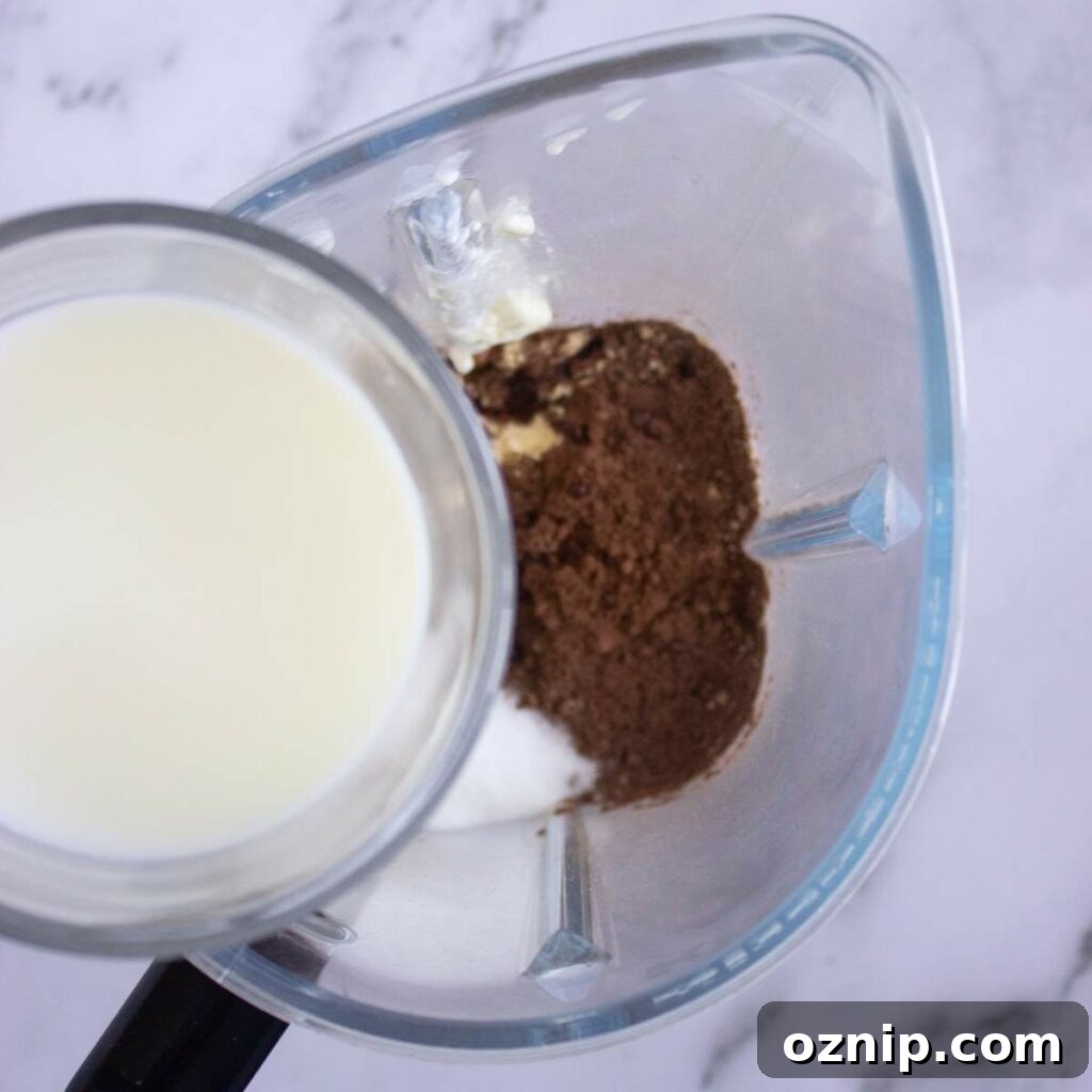 Low Carb Sugar Free Protein Pudding Recipe 11 A blender containing milk, cocoa powder, and protein powder viewed from above.