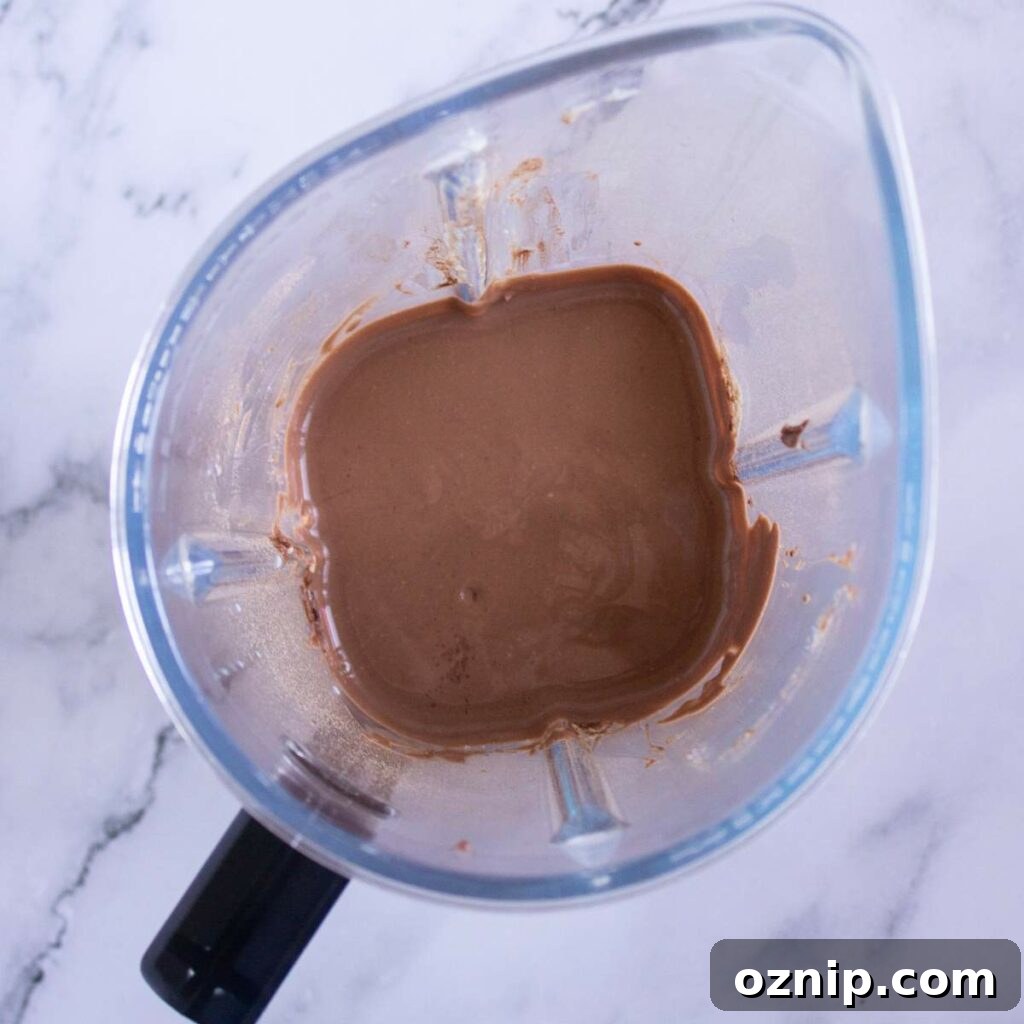 Low Carb Sugar Free Protein Pudding Recipe 12 A blender containing a chocolate pudding mixture sits on a white marble surface.