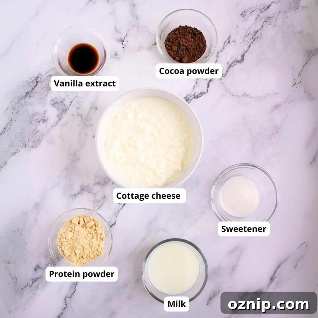 Low Carb Sugar Free Protein Pudding Recipe 5 Six labeled bowls on a marble surface containing vanilla extract, cocoa powder, cottage cheese, sweetener, protein powder, and milk.
