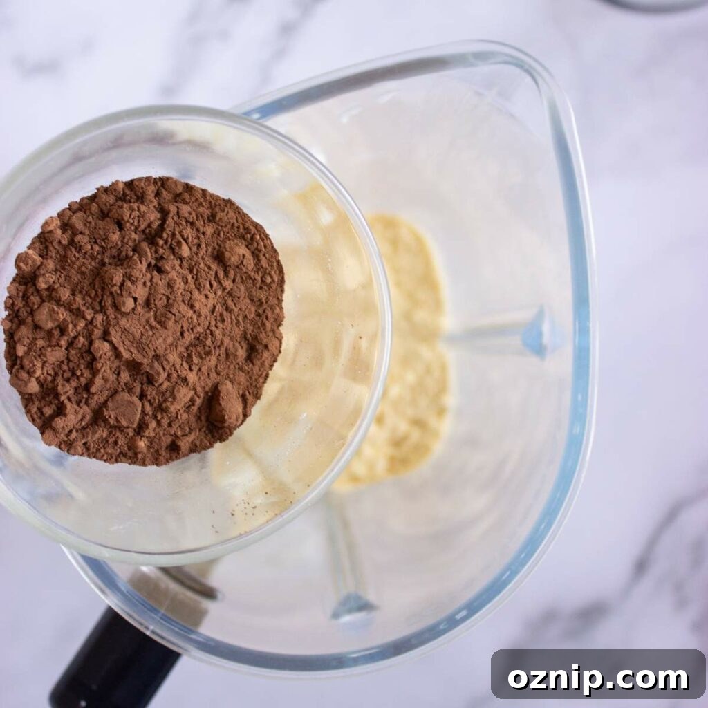 Low Carb Sugar Free Protein Pudding Recipe 8 Cocoa powder is being added to a blender.