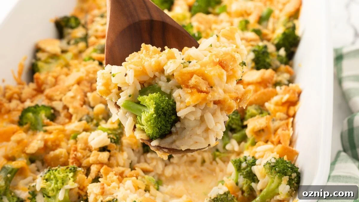 Broccoli rice and cheese casserole in a white baking dish with a wooden spoon.