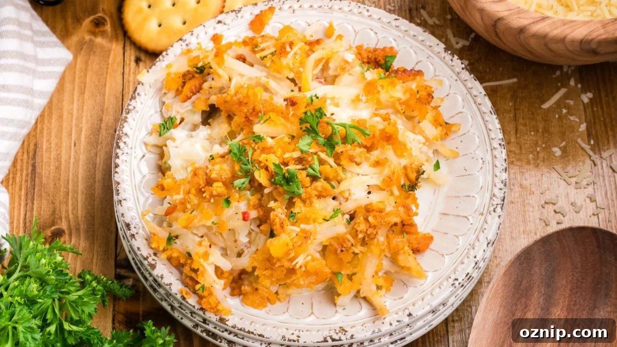 Chicken hashbrown casserole on a white plate with crackers and fresh parsley on the side.