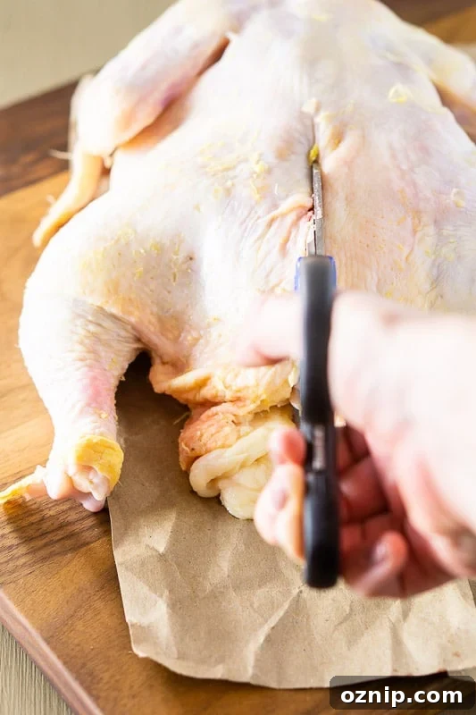 Person spatchcocking a chicken on a cutting board.