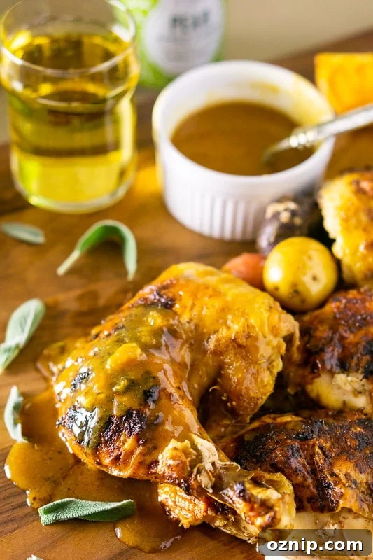 A piece of chicken leg and thigh of a roasted apple cider spatchcock chicken, apple cider gravy on side.