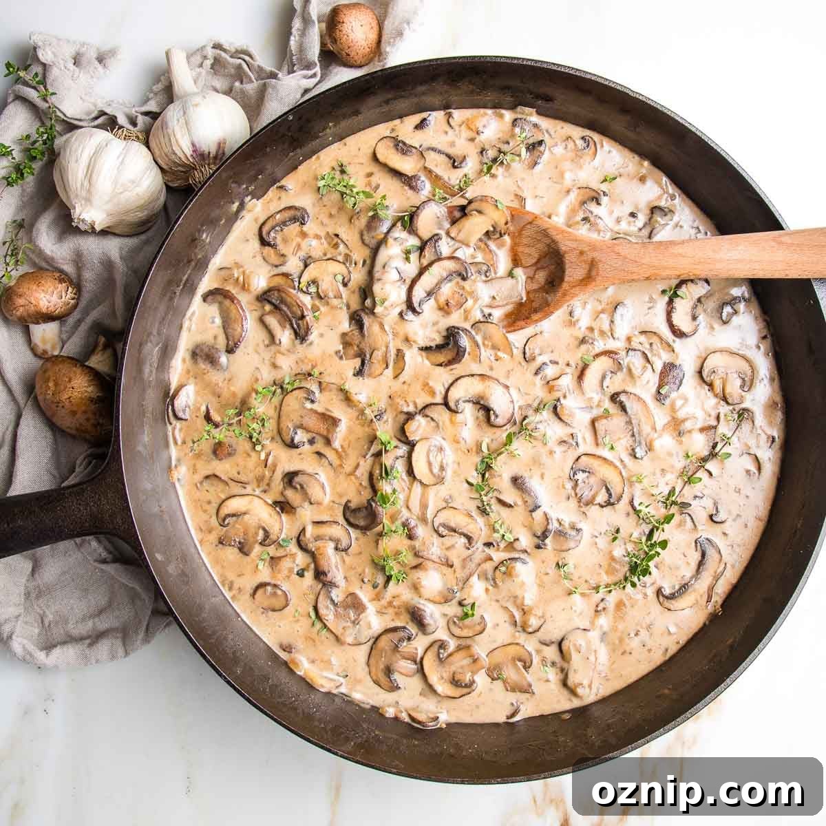 Sliced mushrooms in a creamy brown sauce in a cast iron skillet.