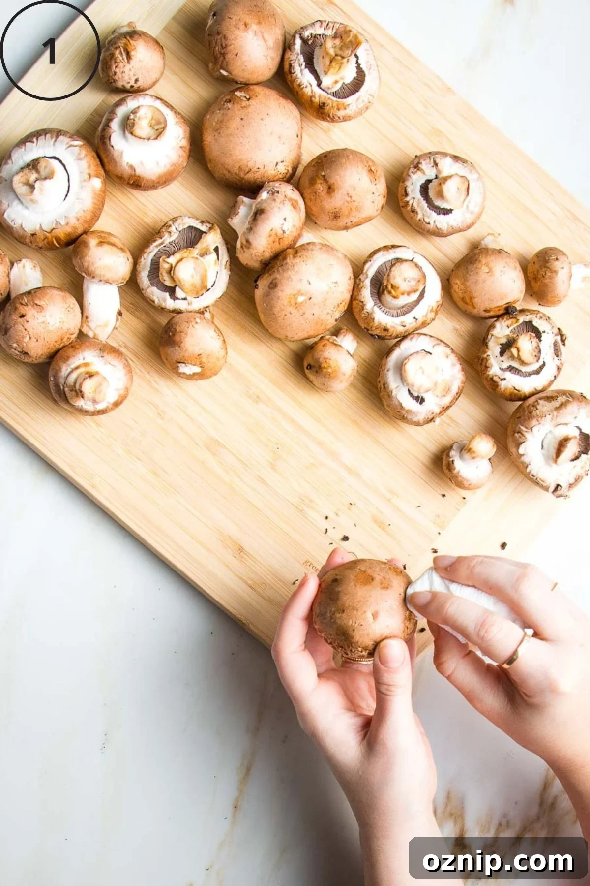 Showing how to clean dirt off baby bella mushrooms with a damp paper towel.