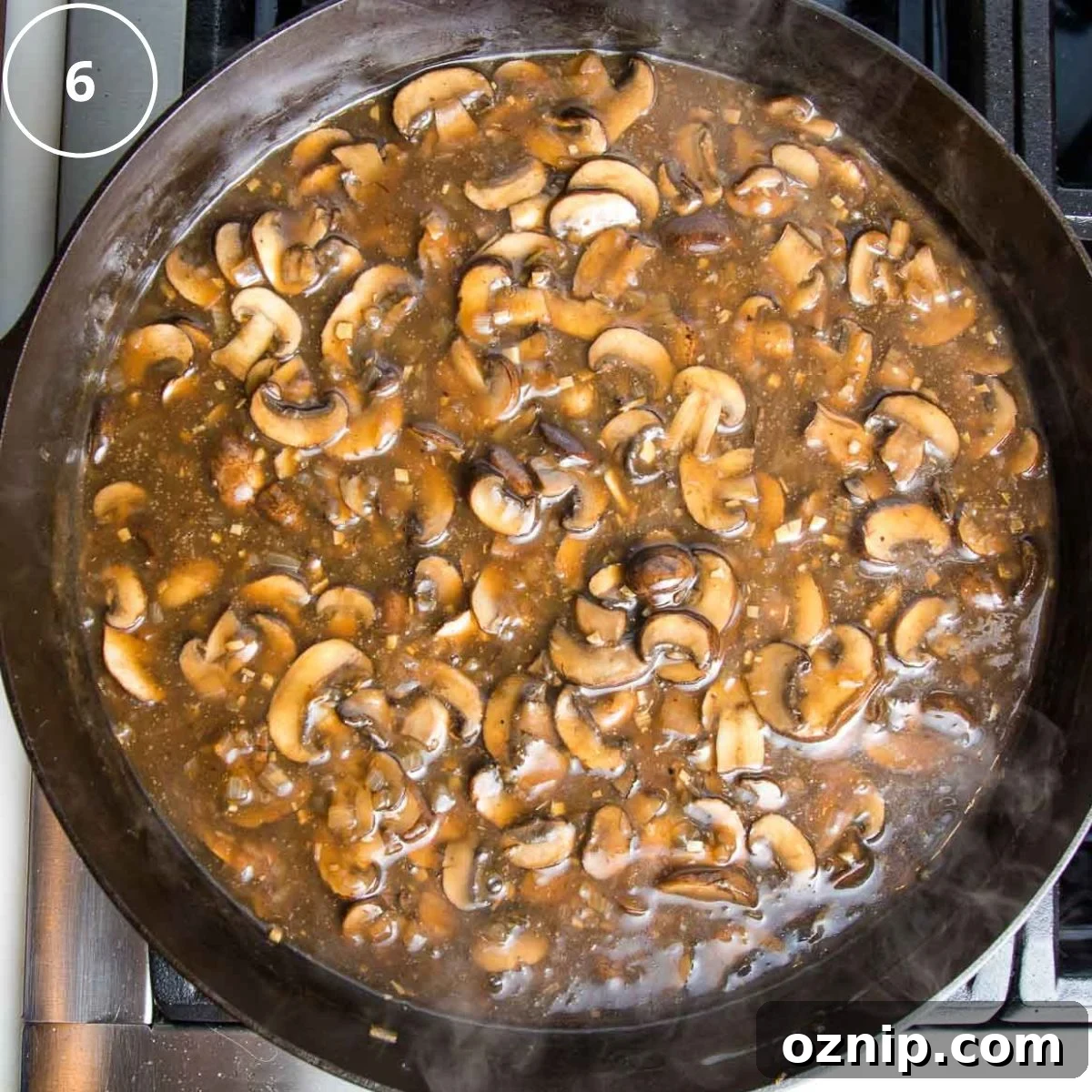 Sliced mushrooms in a brown sauce in a cast iron skillet.