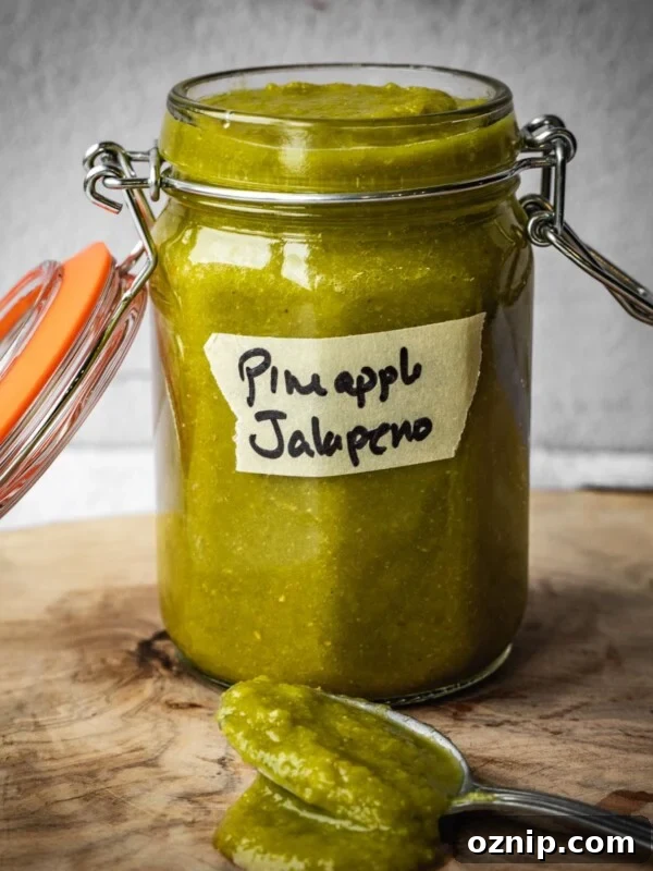 A jar of pineapple jalapeno hot sauce on a wooden board.
